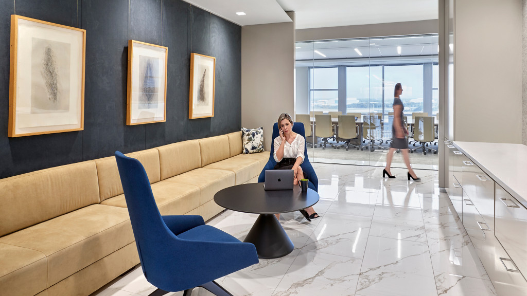 A person sitting on a couch with a laptop in a room with a large window.